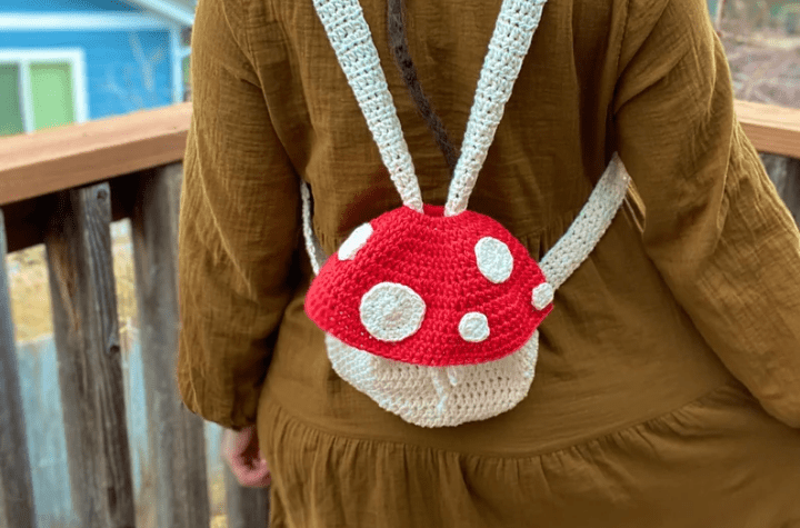 Petit sac à dos champignon au crochet avec un bonnet rouge à pois blancs.