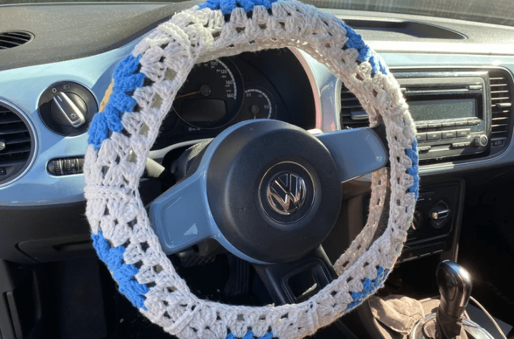 Floral crochet steering wheel cover usine grey, blue, and yellow yarn