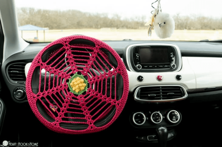 Une housse de volant au crochet de style toile d'araignée avec une fleur au milieu.