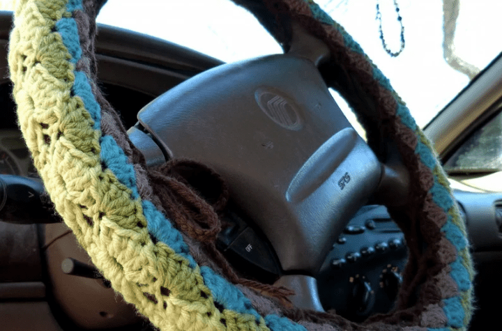 Steering wheel cover using brown, blue, and green yarn