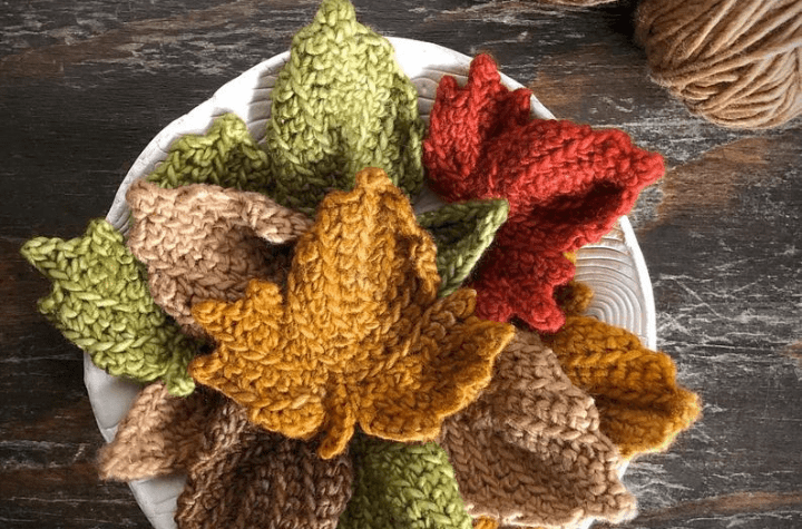 A crochet maple leaf on top of other crocheted leaves.