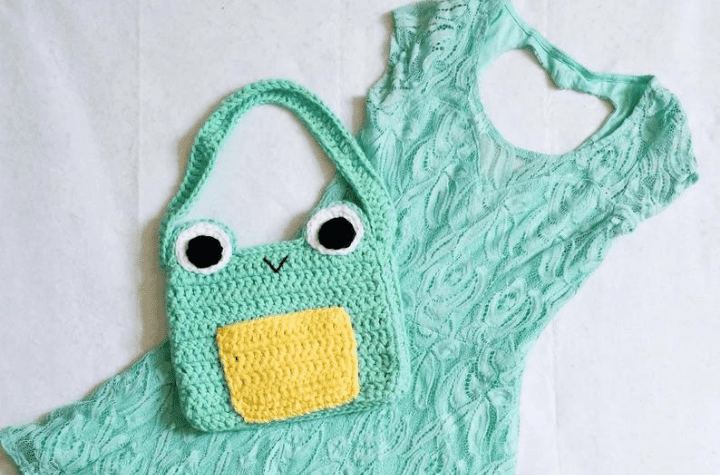 Small frog purse laying on top of dress.