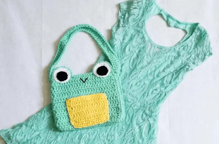 Small frog purse laying on top of dress.