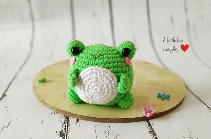 Little crochet frog toy with rosy cheeks.