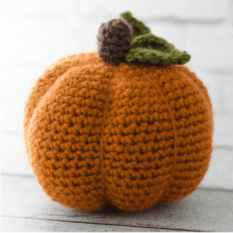 crocheted orang pumpkin with brown stem and green leaves