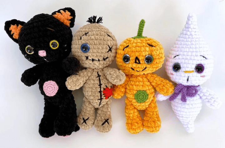Four crochet dolls, one black cat, a voodoo doll, a pumpkin, and a ghost.