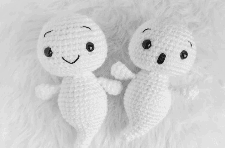 Two crocheted ghosts, one with a little smile and one with a suprised face.