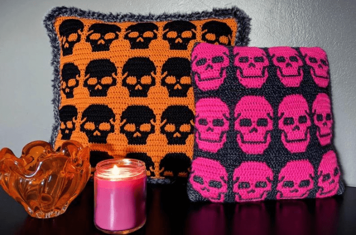 Skull pillows, one with orange and black and one with pink and grey.