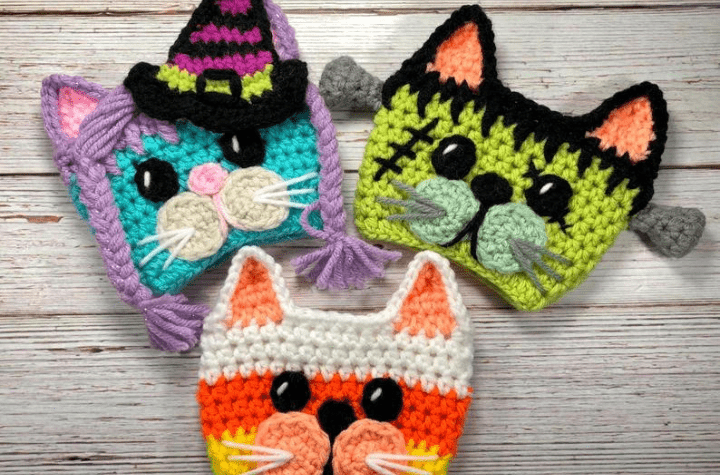A witch cat, frankenstein's monster cat, and a candy corn cat cup cozy.