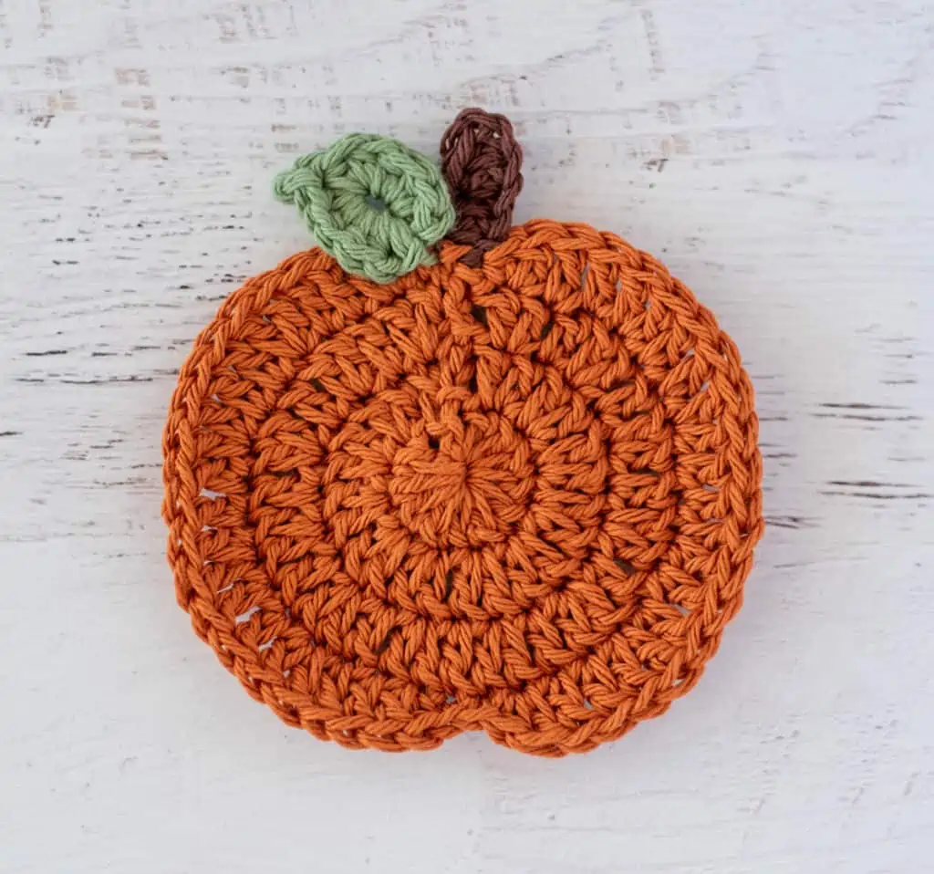 crochet orange pumpkin with brown stem and one green leaf
