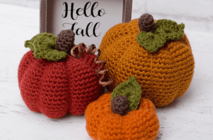 Three different sized crochet pumpkins with a sign that says "hello fall"