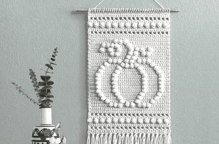 wall hanging that features a crochet pumpkin