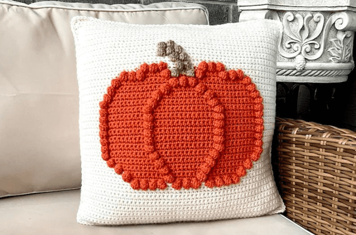 Crochet pillow with a pumpkin on it.