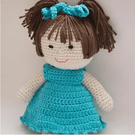 crochet doll with dark brown hair and bright blue dress