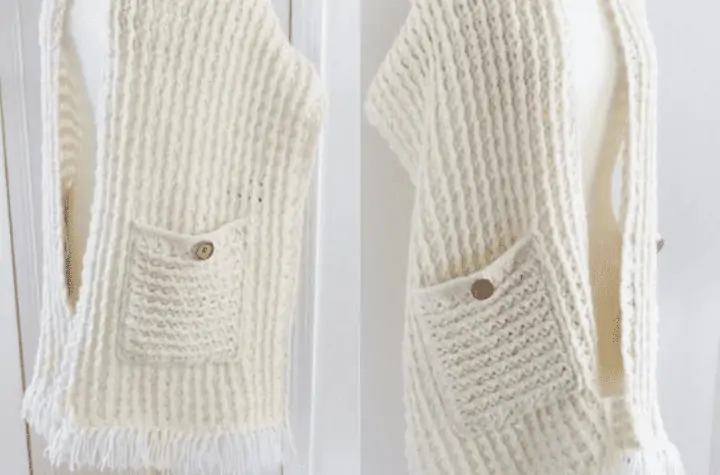 White crochet shawl with fringe and buttons on the pockets.