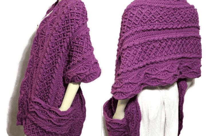 Purple crochet shawl with pockets that features intricate stitches.