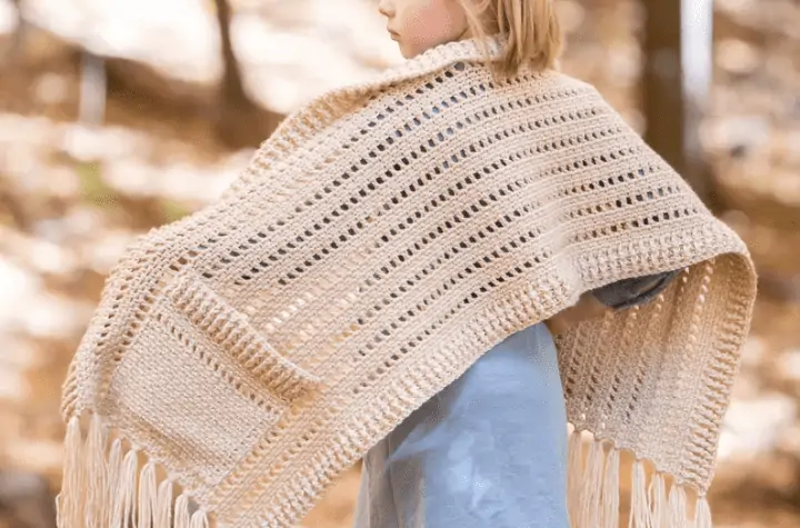 kid's crochet shawl with pockets and fringe using white yarn.