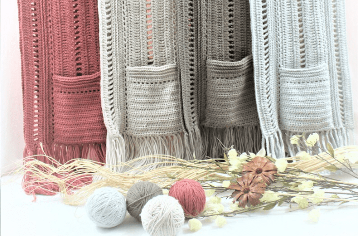 Four crochet pocket shawls in pink and three shades of grey.