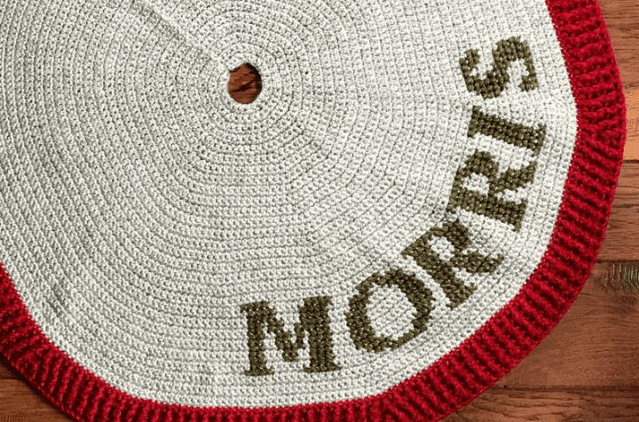 An all white tree skirt with the name "Morris" in green font with a red trim.