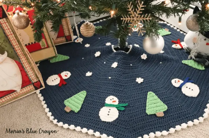 A circular tree skirt with snowmen, trees, and little snowflakes.