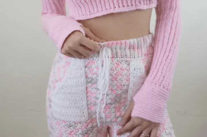 Pink, white, and grey crochet pants with pockets and a matching cropped hoodie.