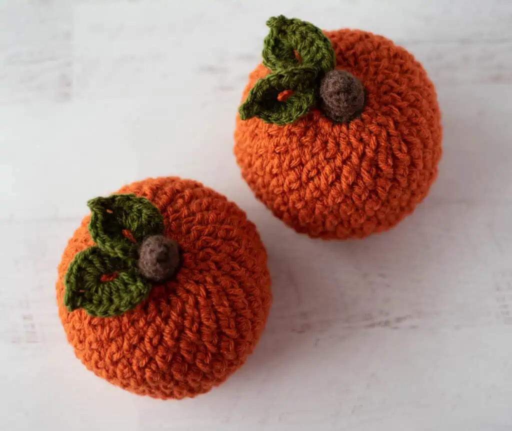 Orange crochet textured pumpkins with brown stem and green leaves