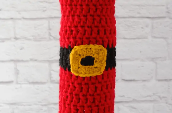 Santa-inpired wine cozy. All red with a gold buckle in the middle.