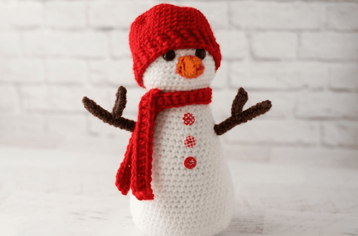 Amigurumi snowman with a red hat and a scarf.