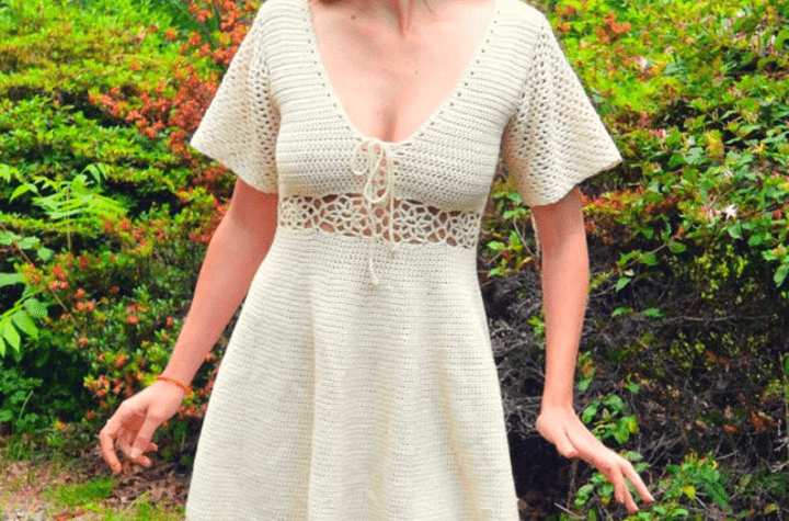 White crochet dress with short sleeves and a flower design along the waist with a tie front.