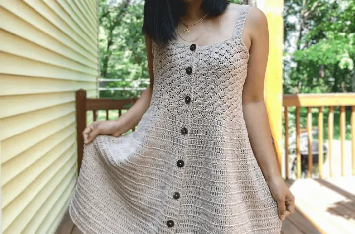 White crochet dress with thing tank top sleeves and buttons going down the center.