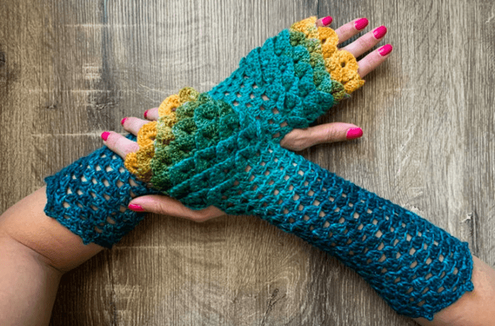 dragon-inspired fingerless gloves that look like scales and form a gradient of color that starts as dark blue, turns to light blue, then green, then finally reaches yellow.