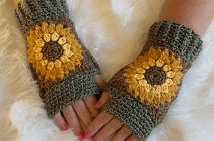Crochet fingerless gloves with a prominent sunflower on the back of the hand.