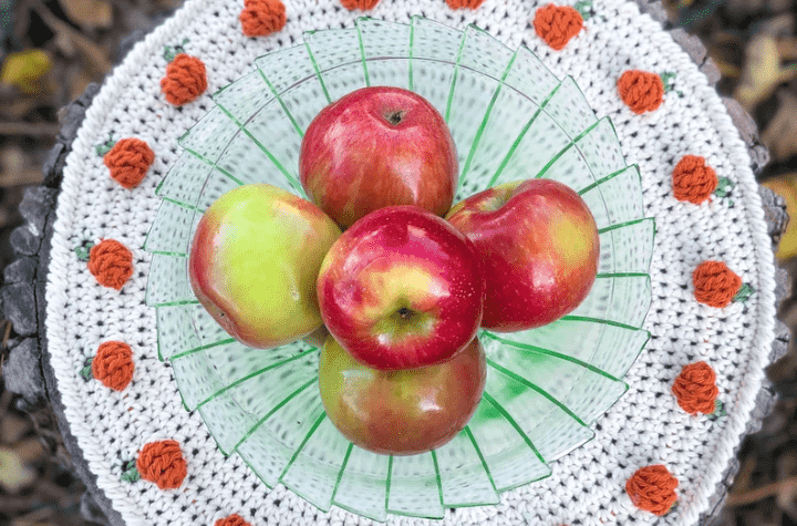 Circular crochet placemat with pumpkins around the border.