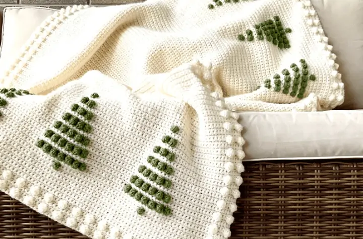 All white afghan with little green pine trees along the top and bottom.