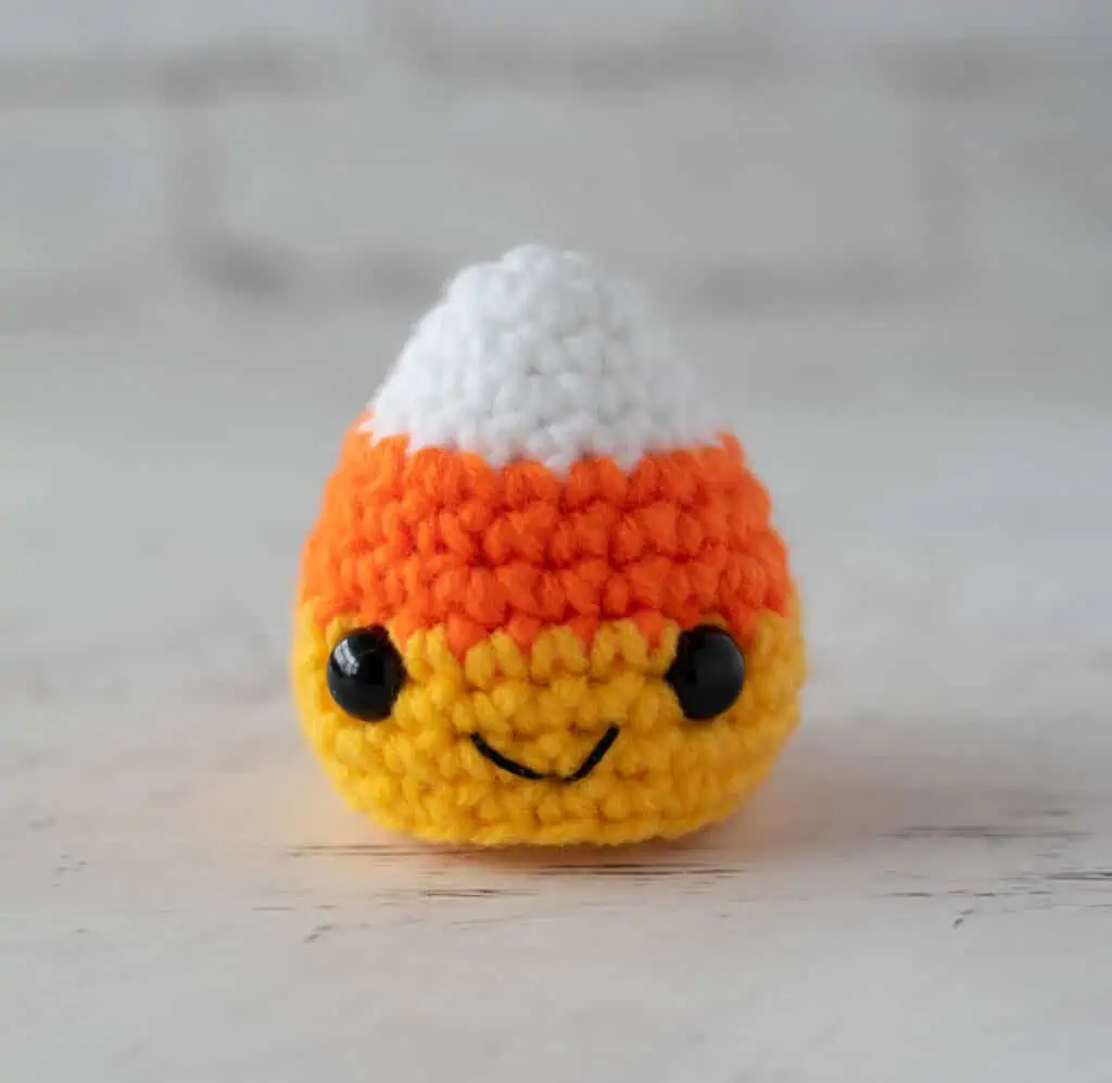 crochet candy corn with black eyes and smile in white, orange and yellow