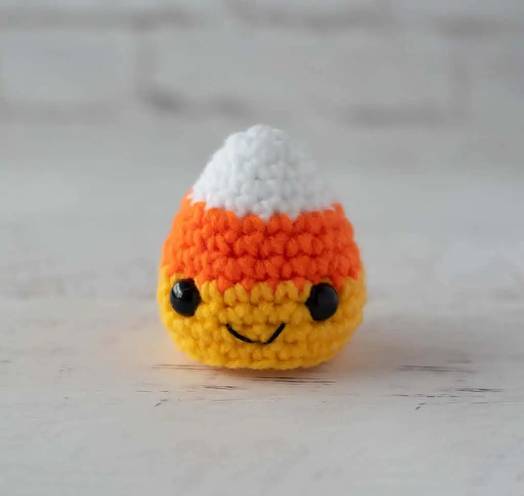 crochet candy corn with black eyes and smile in white, orange and yellow