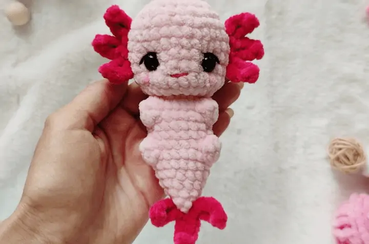 Crochet pink Axolotl that sits in the palm of the hand.