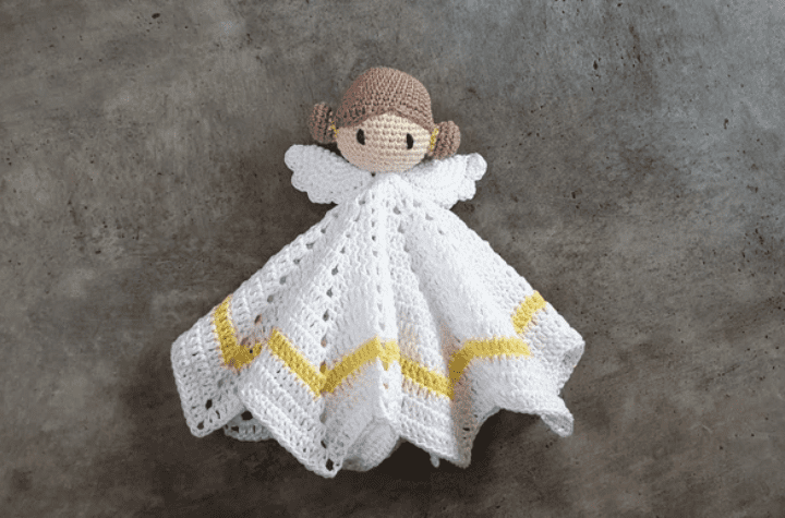 A crochet angel lovey with brunette hair and gold accents.