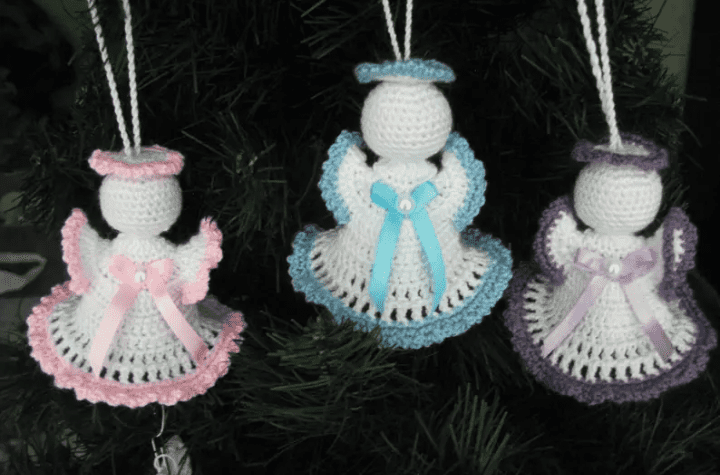 Three crochet angel ornaments, one with pink detailing, one with blue detailing, and one with purple detailing.