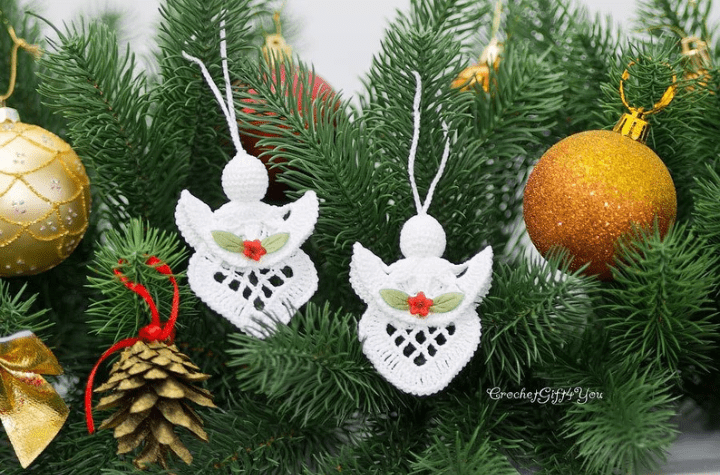 Two crochet angel ornaments with red flowers and two green leaves on them.