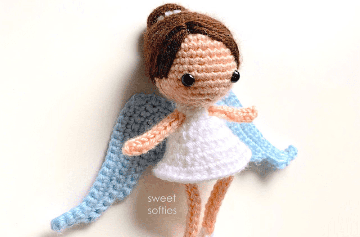 A crochet angel amigurumi with large wings and hair that's in a bun.