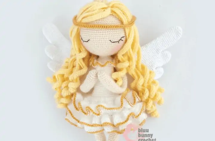 A crochet angel amigurumi with long curly blonde hair and gold accents.