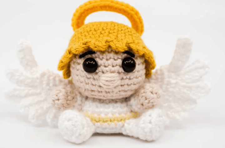 A little crochet angel amigurumi with golden hair and a halo.
