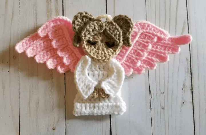A flat crochet angel with pink wings.