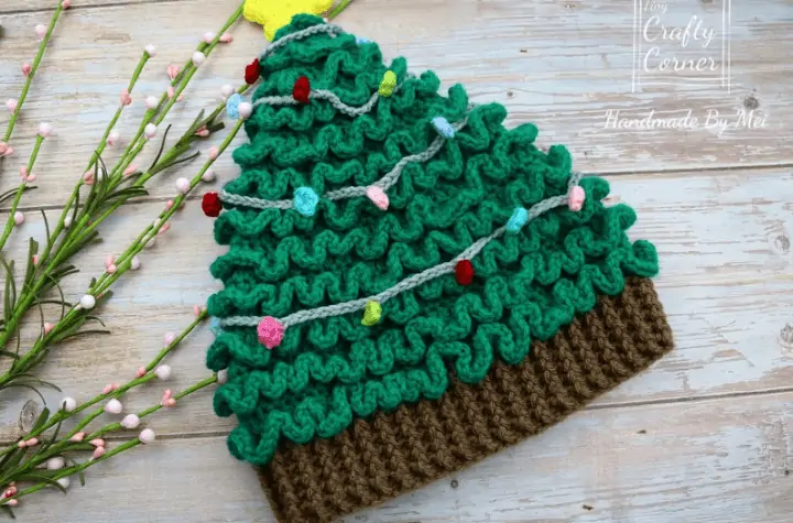 Crochet christmas tree hat that is roughly beanie shaped and has the tree trunk as the rim of the hat