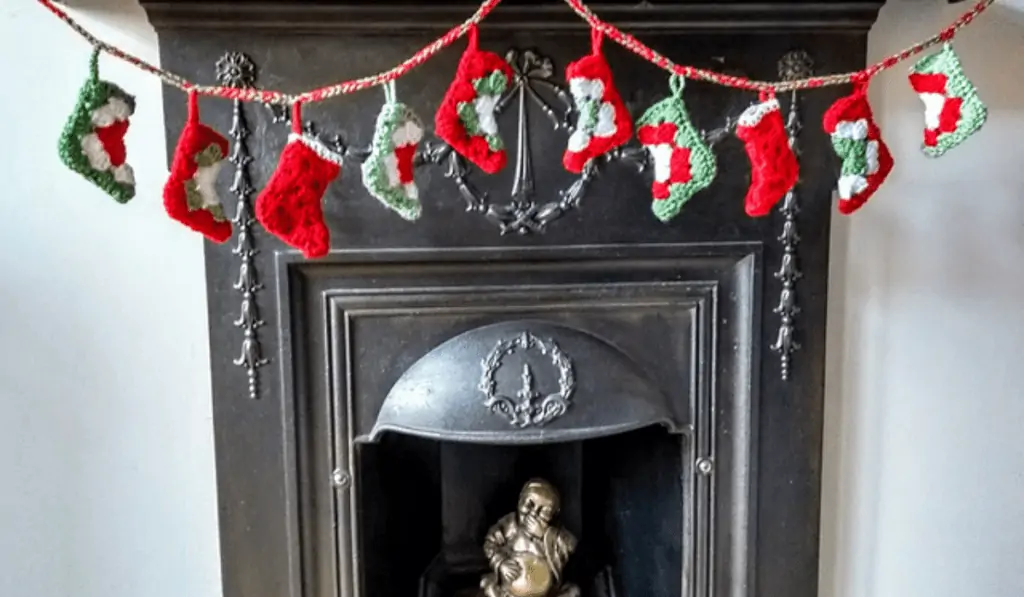 A garland of mini crochet granny square stockings over a fireplace.