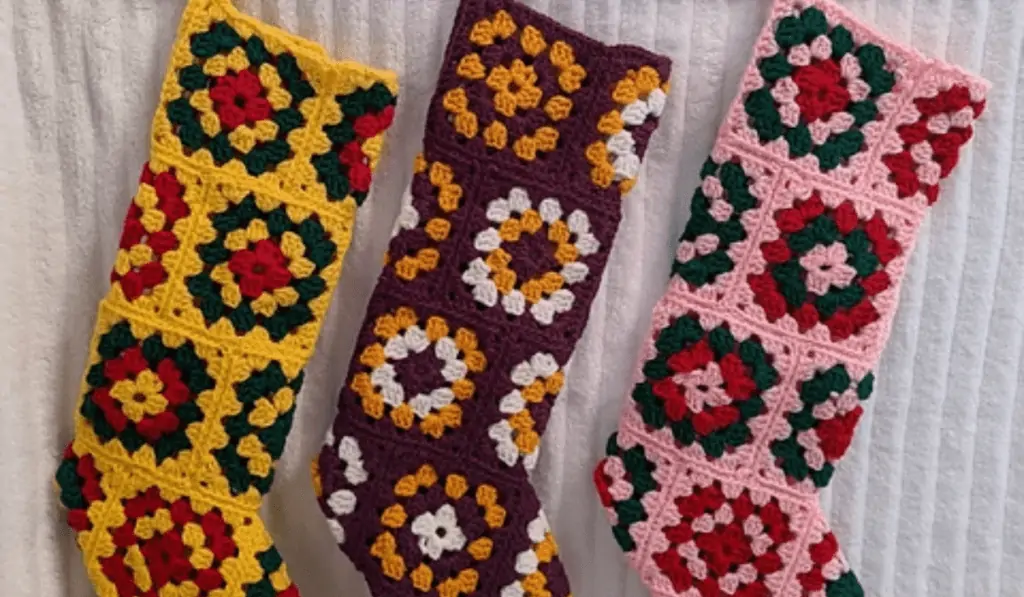 Three crochet granny quare stockings, one in yellow, green, and red; one in marron, white, and yellow; and one granny stocking in green, pink, and red.