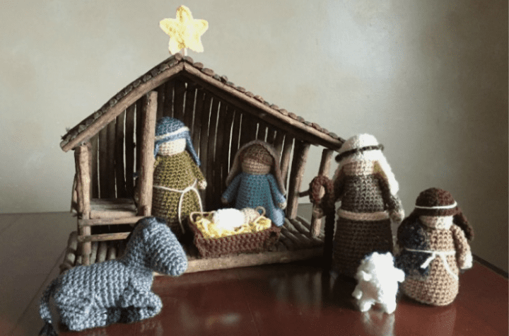 A Crochet nativity set with the holy family, a donkey, a shepard, a lamb, and a man.