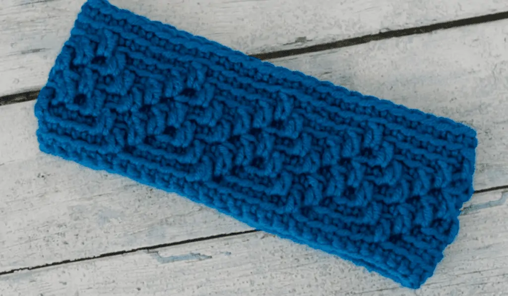 Crochet ear warmer using blue yarn with line stitches.