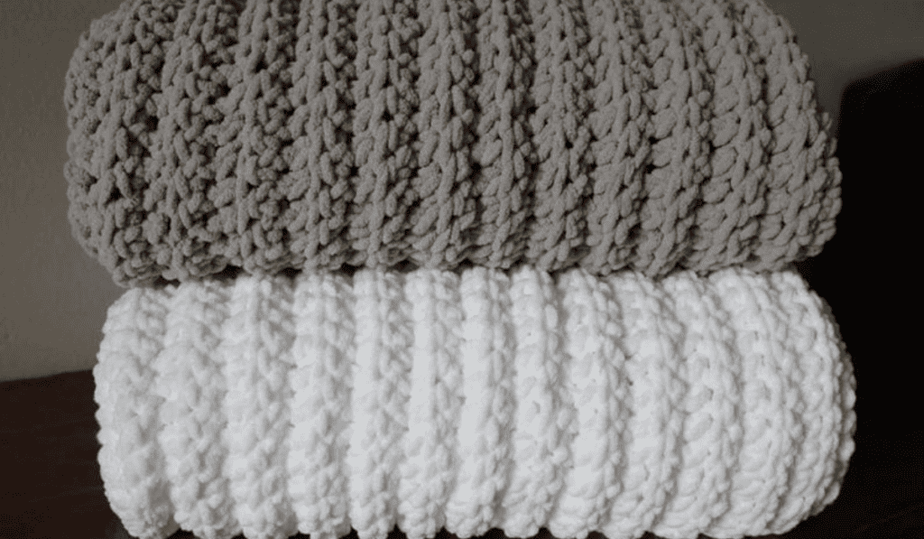 Beige and white crochet blankets folded and stacked on top of each other.